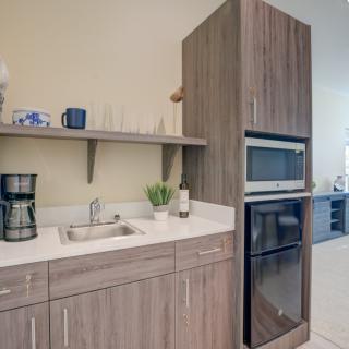 A modern kitchen with wood cabinets featuring a sink, coffee maker, and built-in oven and microwave.