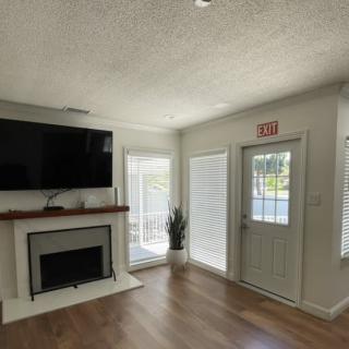 A cozy living room with a fireplace, television, and an abundance of natural light.