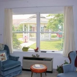 A cozy living room with two blue chairs and a window overlooking a garden.
