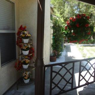 A cozy porch adorned with a five-tier plant stand and a hanging basket full of vibrant flowers.