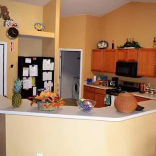 A cozy kitchen interior with wooden cabinets, a black refrigerator, and various decor items on the countertop.