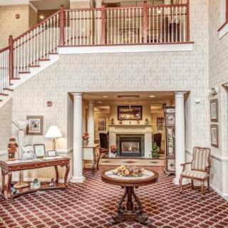A cozy hotel lobby with a central table, elegant decor, and a staircase leading to the upper level.
