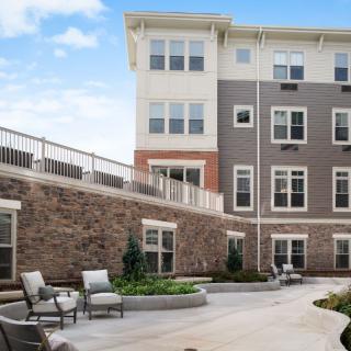 Modern apartment building with outdoor seating and landscaped courtyard.