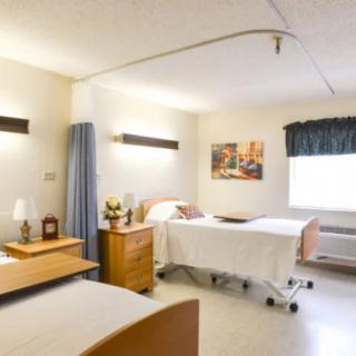 A hospital room with two beds and simple furniture.