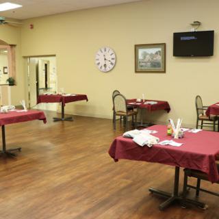 A spacious restaurant dining area featuring neatly arranged tables with red tablecloths and a warm, inviting atmosphere.