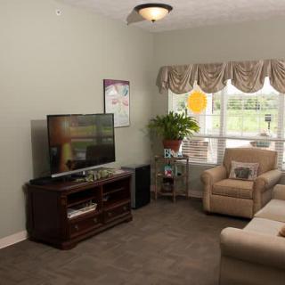A cozy living room with a television, comfortable seating, and a large window.