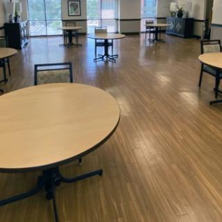 An empty room with round tables and chairs on a wooden floor.