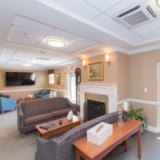 A cozy living room with a sofa, fireplace, and television, featuring modern lighting and decor.