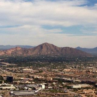 A scenic view of a city with mountains in the background under a partly cloudy sky.