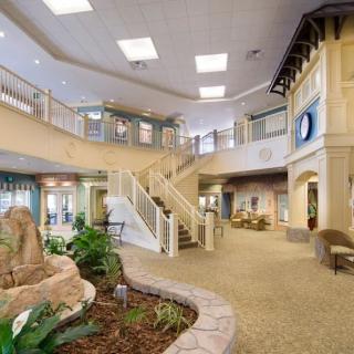 A modern lobby with a central staircase, indoor plants, and elegant lighting.