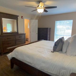 Cozy bedroom with a large bed, dresser, and ceiling fan.