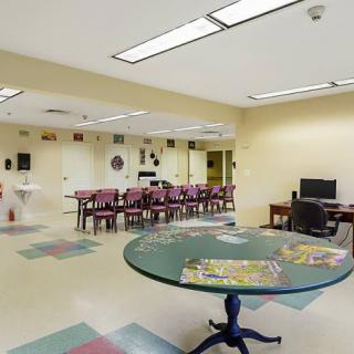 A spacious community room with tables, chairs, and a computer station.