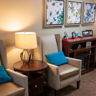 A cozy living room with comfortable chairs, a lamp, and decorative artwork on the wall.