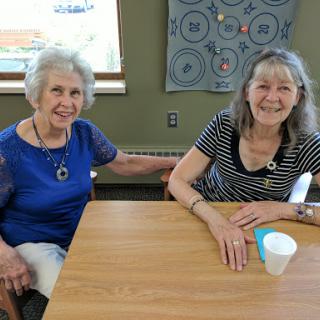 Two friends enjoying their time together at a table, sharing smiles.