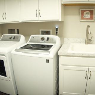 A clean and organized laundry room featuring a washing machine, dryer, and a utility sink.