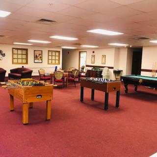 A spacious game room featuring foosball and pool tables with comfortable seating areas.