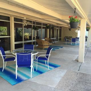 A cozy patio with blue-accented furniture and hanging plants under a covered area.