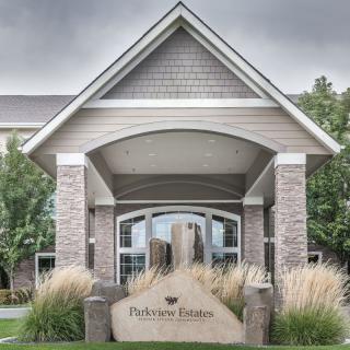 Entrance of a modern building with a welcoming sign and landscaped surroundings.