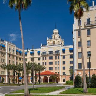 A grand hotel with elegant architecture surrounded by palm trees under a clear blue sky.