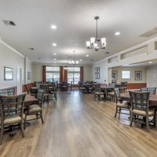 A spacious dining area with neatly arranged tables and chairs, featuring elegant lighting and wooden flooring.