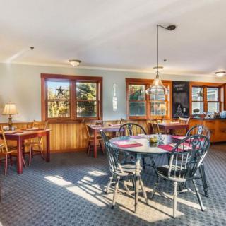 A cozy dining area with wooden furniture and ample natural light streaming in through large windows.