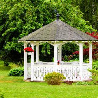 A charming white gazebo surrounded by lush greenery in a garden setting.