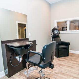 A cozy and modern hair salon setup featuring a styling station, a barber chair, and a hair dryer.