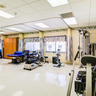 A well-equipped physical therapy room featuring various exercise machines and a bright, spacious environment.