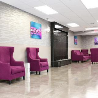 A stylish and modern lobby featuring purple chairs and a calming water feature.