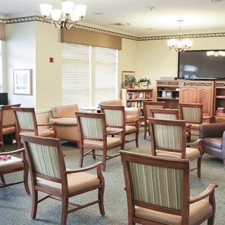 A spacious lounge area with arranged chairs and a television for guests.