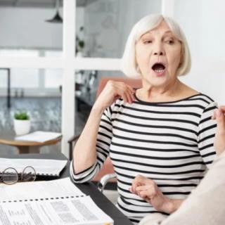 Surprised senior woman in an office setting during a conversation.