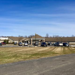 A welcoming facility with a spacious parking area set against a clear blue sky.