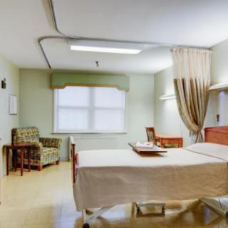 A spacious and well-lit hospital room with a bed and seating area.