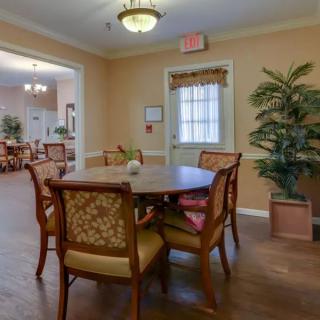 A cozy dining area with a wooden table surrounded by chairs, indoor plants, and warm lighting.