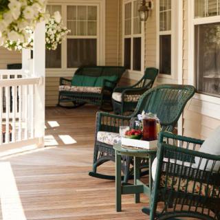 A cozy porch with wicker furniture and a wooden floor, perfect for relaxation.