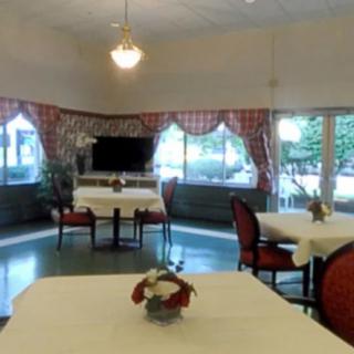Cozy dining area with tables and chairs, featuring decorative curtains and overhead lighting.