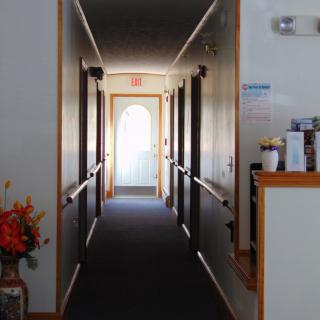 A quiet hallway with doors leading to various rooms, ending in a glass door letting in natural light.