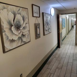 A hallway decorated with framed floral artwork and other wall hangings.