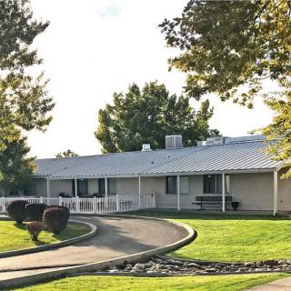 A single-story house with a curved driveway and well-maintained lawn.