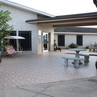 A spacious outdoor patio featuring a decorative swing, stone table, and seating area.