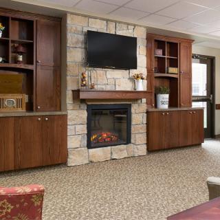 A cozy living room with a fireplace, stone wall, and built-in wood cabinets.