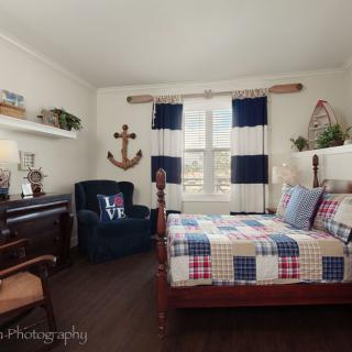A cozy nautical-themed bedroom featuring wooden furniture and an anchor decoration on the wall.