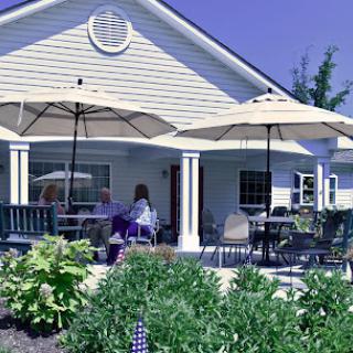 A cozy outdoor seating area featuring umbrellas, surrounded by lush greenery and flowers.