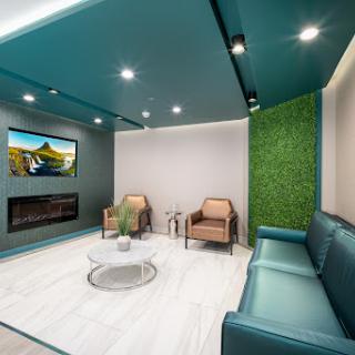 A modern lounge area featuring comfortable seating, a television, and a touch of greenery.