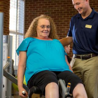 A personal trainer assists an older adult in a fitness session at the gym.