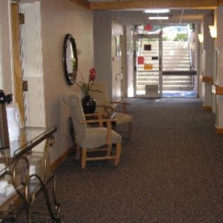 A cozy hallway with chairs, a mirror, and an entrance in the distance.