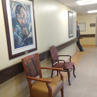 A quiet hallway featuring chairs and artwork, creating a welcoming waiting area.