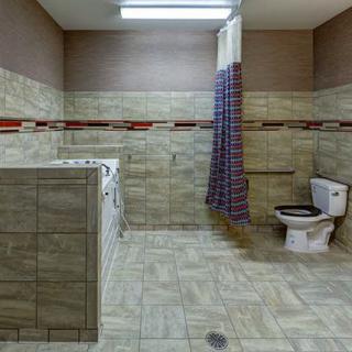 A spacious bathroom with a tiled design featuring a toilet, shower area, and curtain.