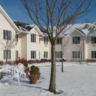 A snowy residential area with houses and leafless trees.