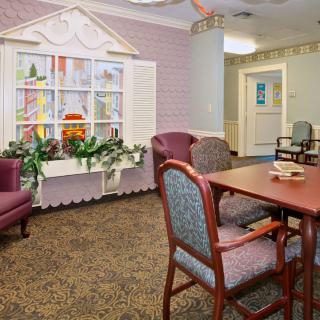 A cozy room with a table surrounded by chairs, decorated with plants and a window display.